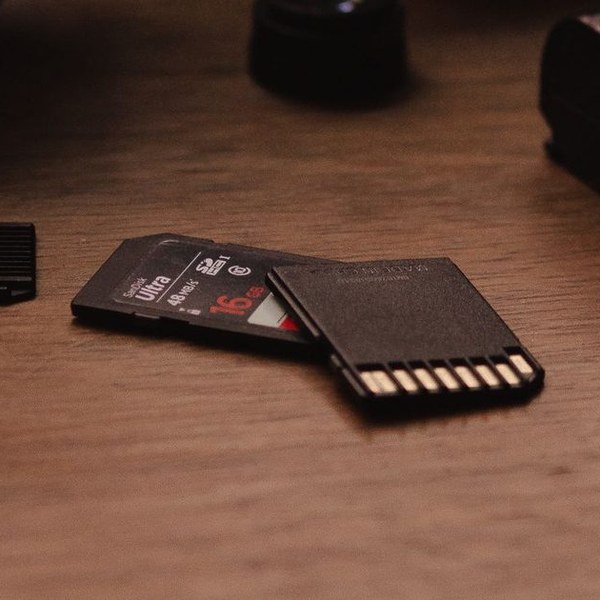 Deleted Photos on an SD Card? How to Get Them Back — Free 3 Camera lenses and SD cards on a desk — recovering deleted photos from a memory card